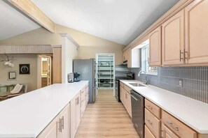 Eine Küche mit Holzausstattung, einer weißen Arbeitsplatte und einem eingebauten Geschirrspüler.