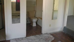 A bathroom with a toilet, a shower, and a mirror.