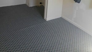 A room with a patterned floor, a door, and a window with a curtain.