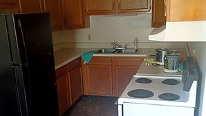 A kitchen with wooden cabinets, a black refrigerator, a white stove, and a sink.
