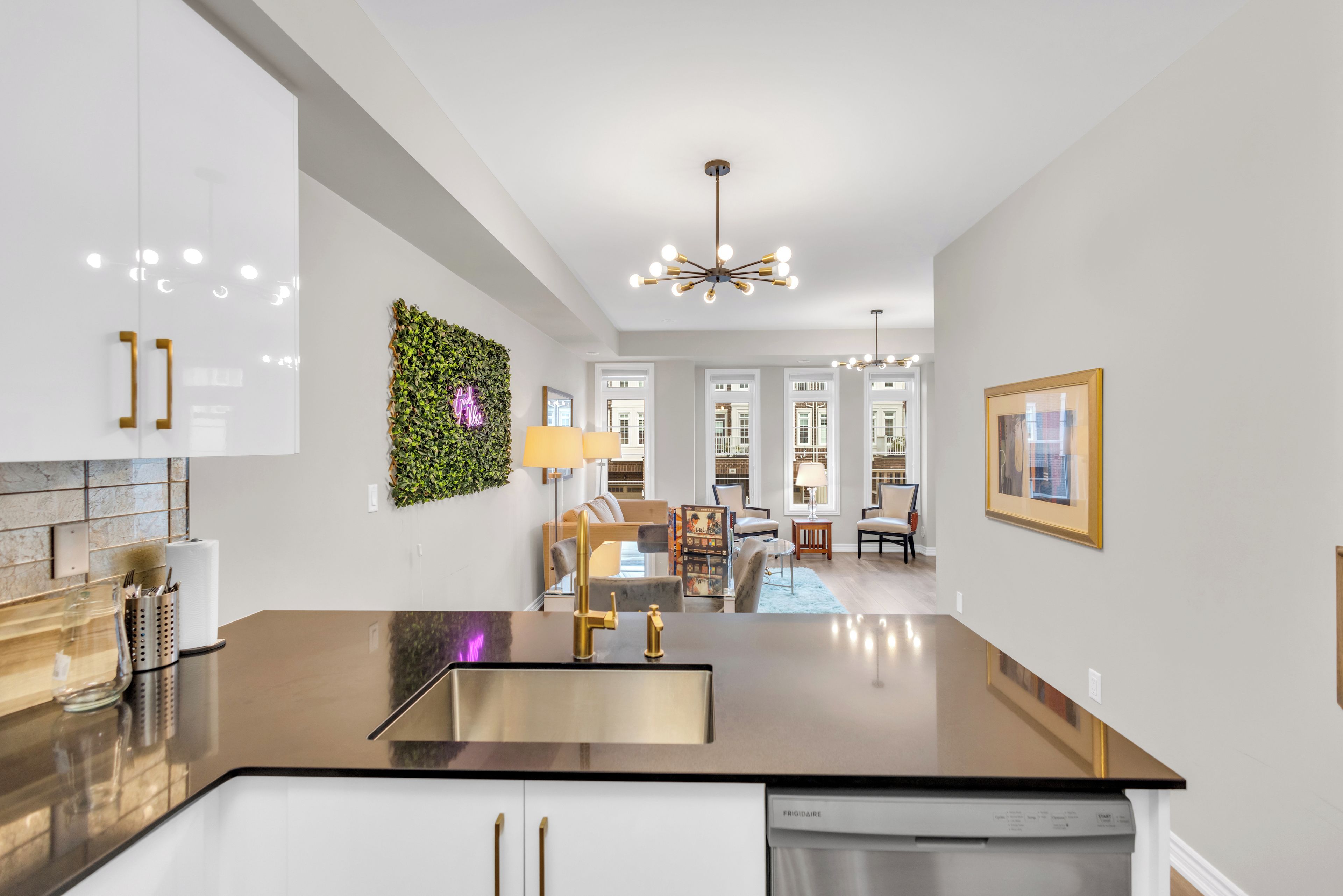 A modern kitchen with a central island, white cabinetry, and a green wall decoration.