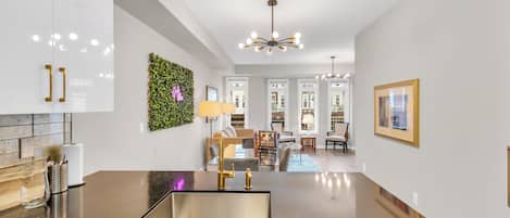 Una cocina moderna con una isla central, armarios blancos y un adorno de pared verde.