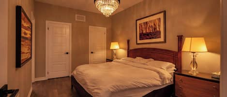 Habitación de hotel con una cama grande, dos mesitas de noche con lámparas, un candelabro y un cuadro en la pared.