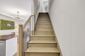 A staircase with a wooden handrail and a wall-mounted light fixture. - Bright 3BR Home with Balcony & Free Parking (Bradford West Gwillimbury)