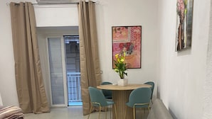A living room with a sofa, a dining table with chairs, a red vase, and a painting on the wall. - Basile House: elegance and comfort in the center of Naples (Napoli)