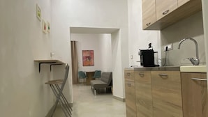 A narrow hallway with a kitchen area featuring wooden cabinets and a sink. - Basile House: elegance and comfort in the center of Naples (Napoli)