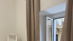 A room with a large mirror, beige curtains, and a sliding glass door leading to an outdoor area. - Basile House: elegance and comfort in the center of Naples (Napoli)