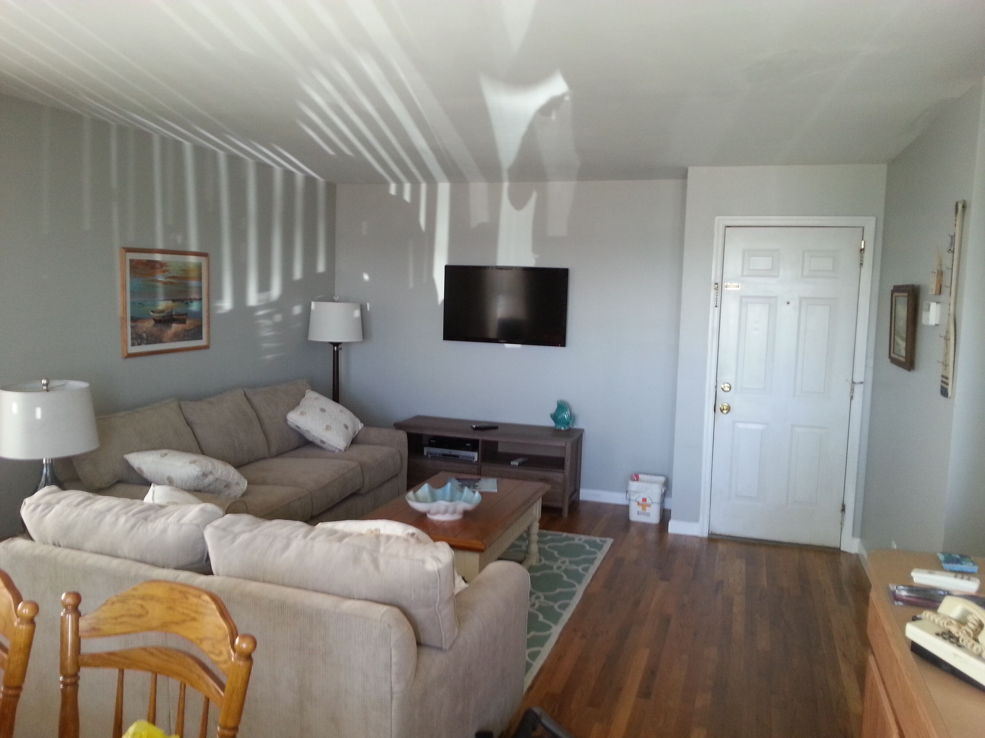 A living room with a sofa, a coffee table, a flat-screen TV, and a door.