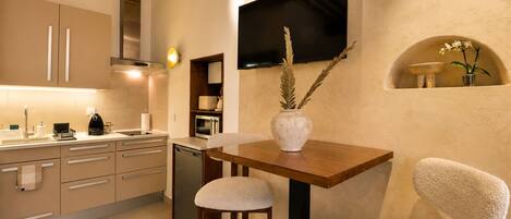 A modern kitchen with a flat-screen TV, a dining area with stools, and a decorative vase on the table.