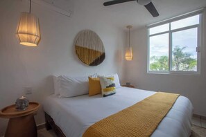 A bedroom with a bed, bedside tables, a wall-mounted circular artwork, and a window with a view. - Riviera Nayarit Brand New House Close To The Beach (Bucerías)