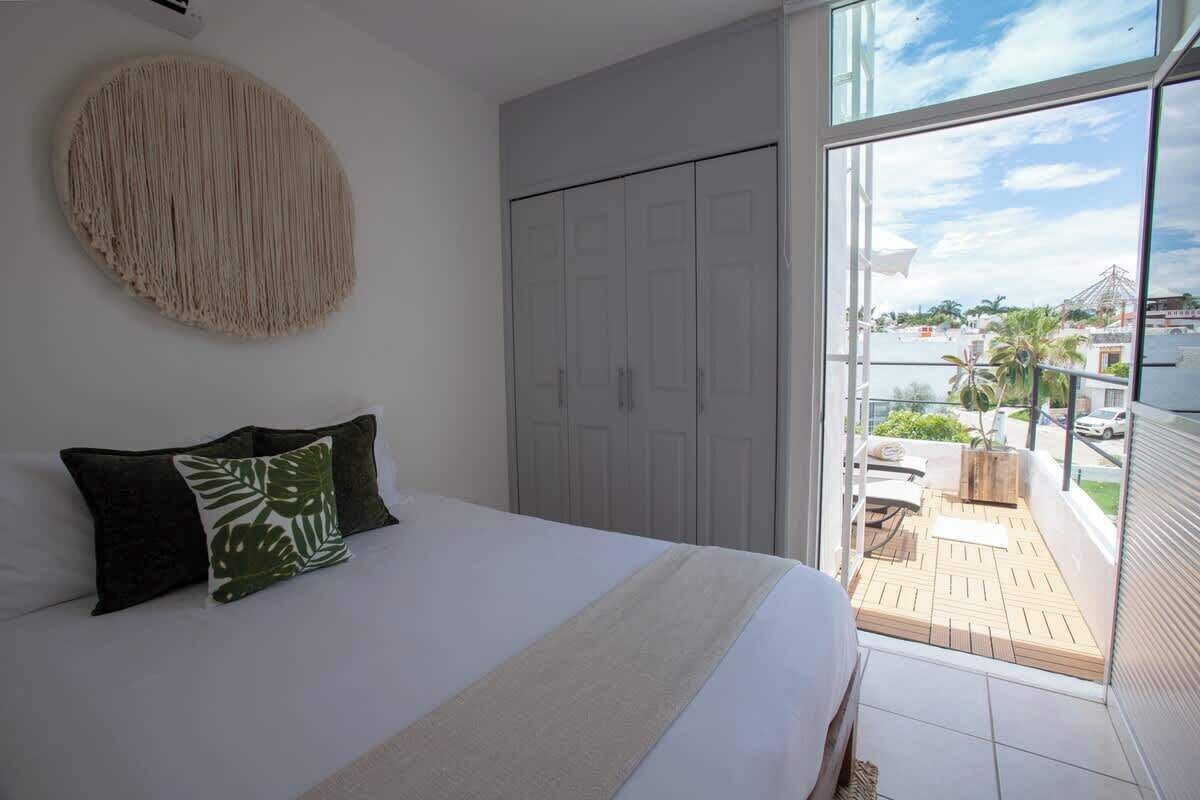 A bedroom with a bed, a wardrobe, and a balcony with a view.
