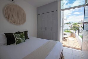 Quarto com cama, armário e varanda com vista.
