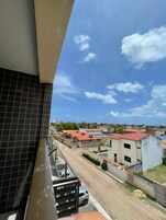Un balcone con vista su una zona residenziale, una strada e un edificio con tetto rosso.