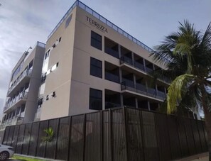 Un edificio de varios pisos con balcones, un cartel con el nombre 'TERRAZZA' y una entrada con reja.