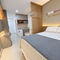 Una habitación de hotel con cama, escritorio con microondas, kitchenette pequeña y puerta corredera.