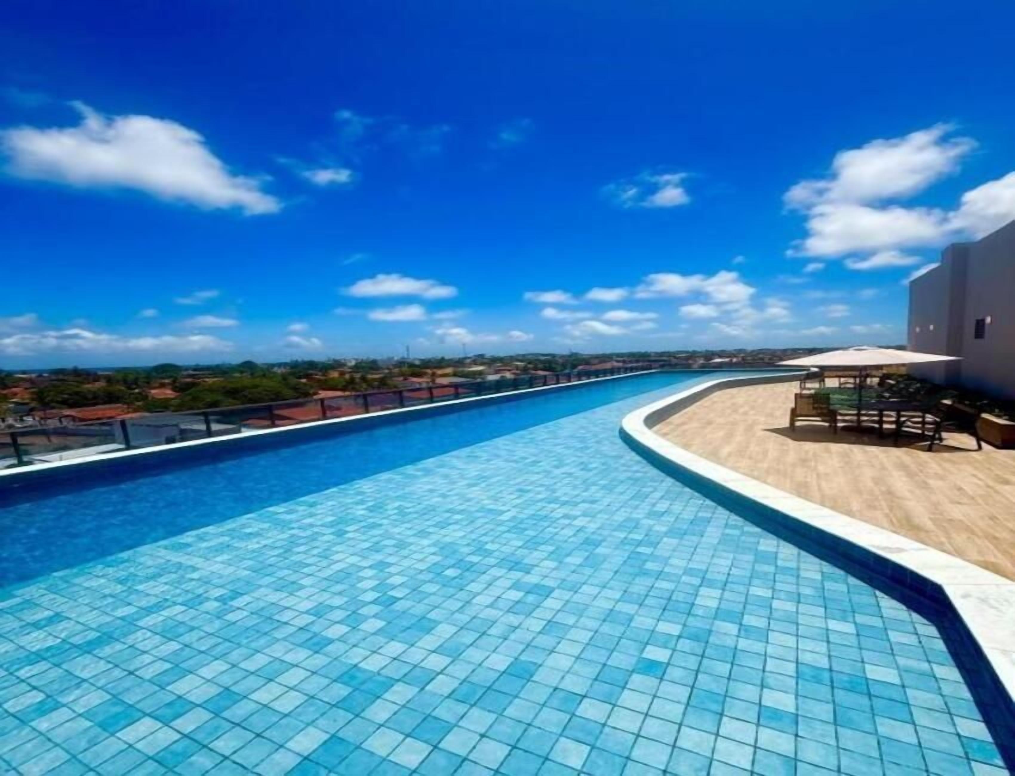 Ein Schwimmbecken mit Fliesenboden, geschwungener Kante und Blick auf die umliegende Landschaft.