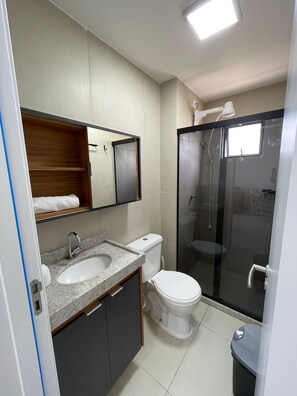 Un baño moderno con lavamanos, inodoro y cabina de ducha de vidrio.