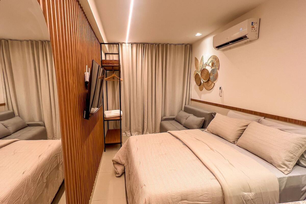 Habitación de hotel con dos camas, un armario, un espejo y un equipo de aire acondicionado.