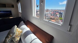 A room with a bed, a window with a view of a cityscape, and an air conditioning unit. - eXperience Átic Valencia (València)