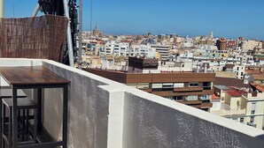A balcony with a table and chairs, overlooking a densely packed urban area with various buildings. - eXperience Átic Valencia (València)
