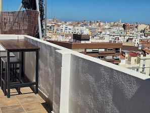 A balcony with a table and chairs, overlooking a densely packed urban area with various buildings. - eXperience Átic Valencia (València)