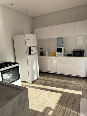 A modern kitchen with white cabinetry, a built-in oven, a microwave, and a water dispenser. - COZY HOUSE COMPLETE IN ARRAIAL DAJUDA (PORTO SEGURO)