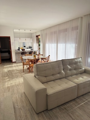A modern living room with a sofa, dining table, chairs, and a kitchen area. - COZY HOUSE COMPLETE IN ARRAIAL DAJUDA (PORTO SEGURO)