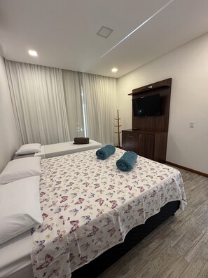 A hotel room with a bed, a TV mounted on the wall, and a window with curtains. - COZY HOUSE COMPLETE IN ARRAIAL DAJUDA (PORTO SEGURO)