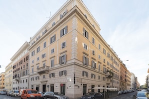 Un edificio de varios pisos con entrada en esquina, varias ventanas y escaparate visible.