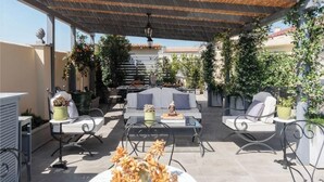 Eine Terrasse im Freien mit Sitzgelegenheiten, einem Tisch und Kübelpflanzen.