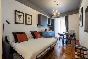 Un dormitorio pequeño con cama, mesita de noche y una pequeña zona de escritorio con sillas.