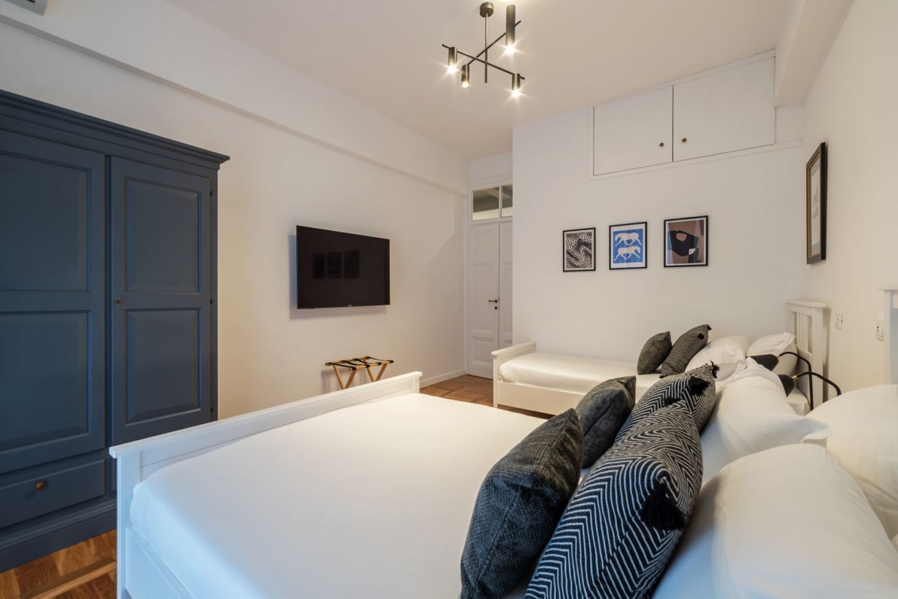 A bedroom with a large bed, a wardrobe, a television, and a wall-mounted artwork.