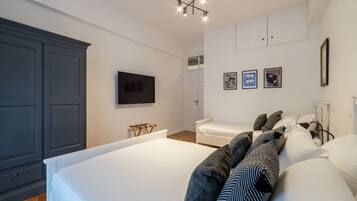 A bedroom with a large bed, a wardrobe, a television, and a wall-mounted artwork.