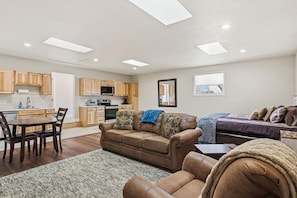 A spacious living area with a sofa, a dining table, and a kitchen in the background. - Ranch Studio Retreat with Mountain Views, Longmont, Colorado (Longmont)