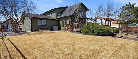 A two-story house with a green exterior, a covered porch, and a well-maintained lawn.