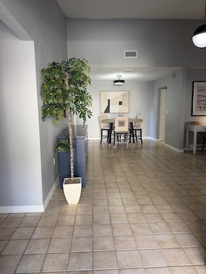 Un couloir comprenant un coin repas, une plante en pot et un luminaire au plafond.