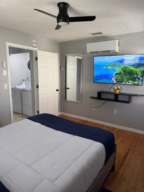 Ein Schlafzimmer mit Bett, Deckenventilator, Fernseher und Klimaanlage.