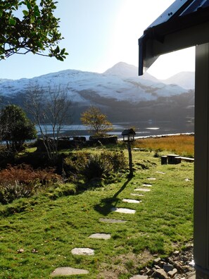 Ein Garten mit einem Kiesweg, einem Pavillon und Blick auf schneebedeckte Berge.