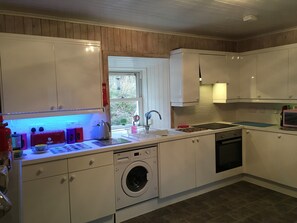 Eine kleine Küche mit Waschmaschine, Spüle und Fenster.