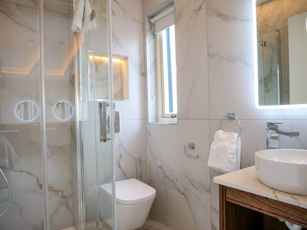 Een badkamer met een douchecabine, toilet, wastafel en spiegel.