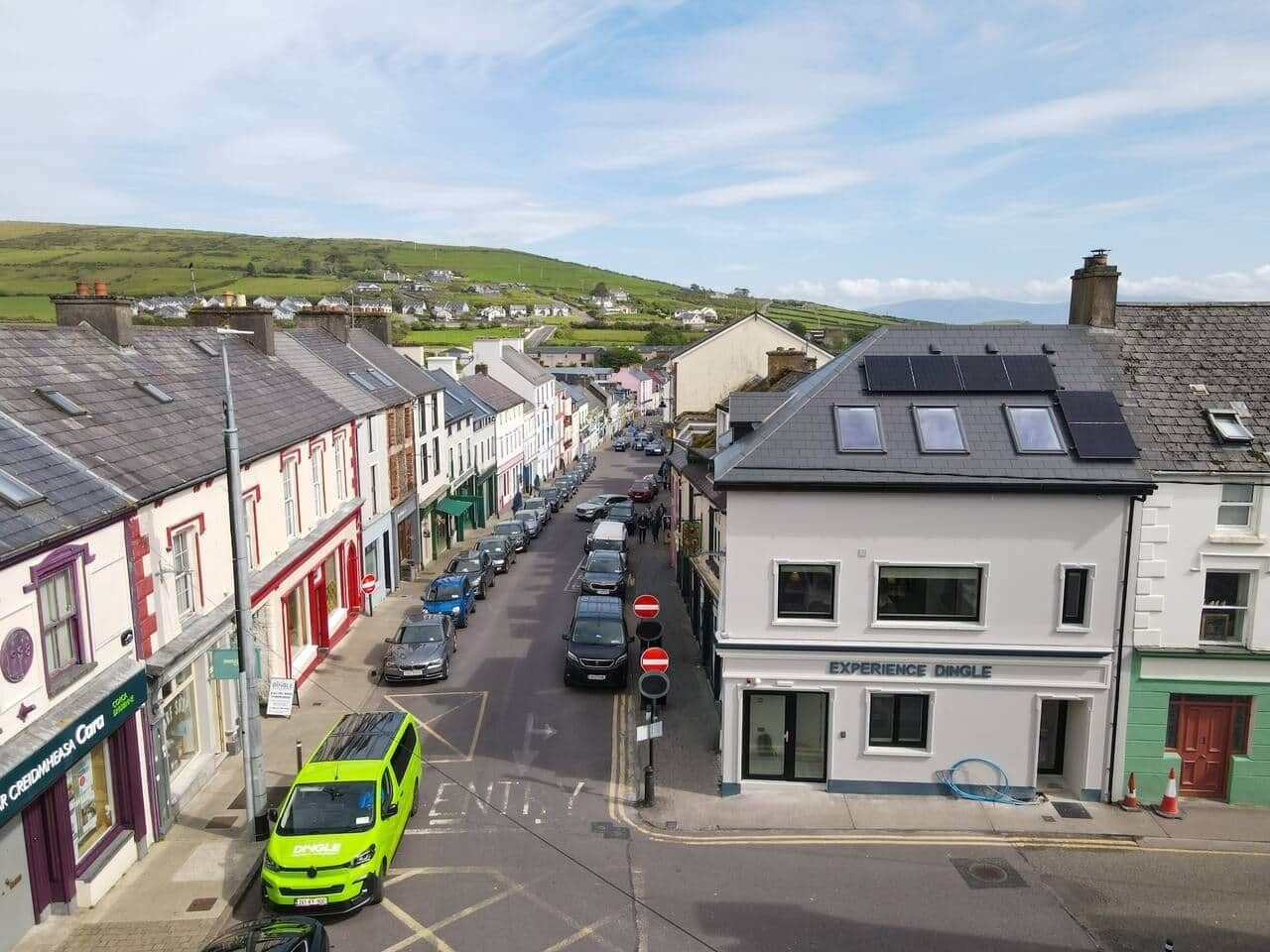 A street view with buildings, parked cars, and a clear sky.