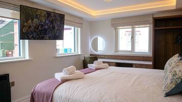 Une chambre d’hôtel avec un grand lit, un miroir rond et un lustre.
