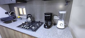 Eine Küche mit Gasherd, Wasserkocher, Kaffeemaschine und Mixer.