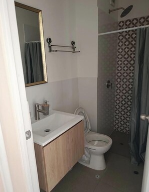Ein Badezimmer mit Toilette, Waschbecken, Spiegel und Dusche.