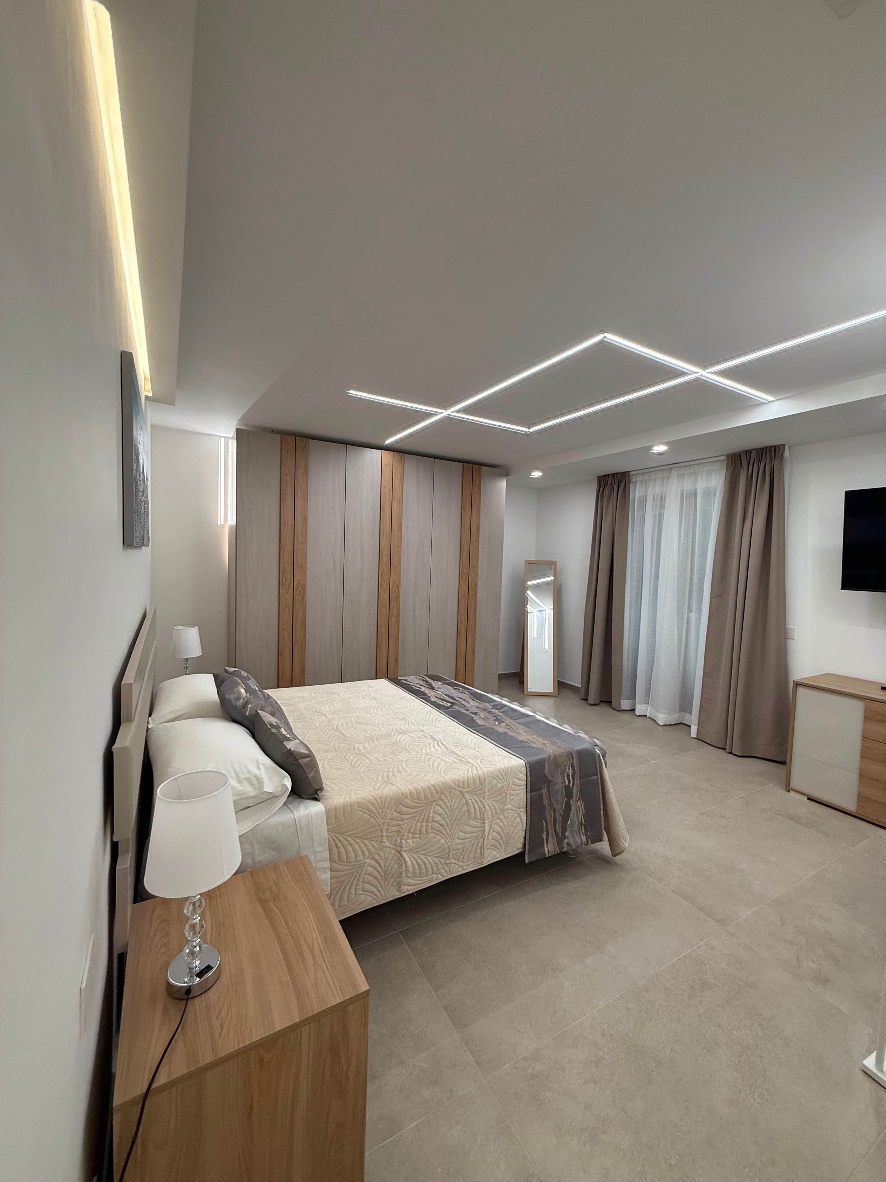 Una camera da letto moderna con un letto grande, comodini, uno specchio e una televisione.