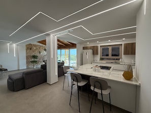 A modern kitchen with a central island, bar stools, and a stone accent wall.