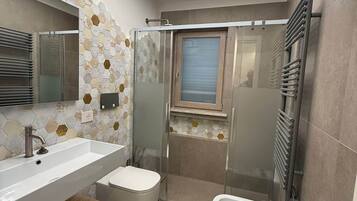 A modern bathroom with a large mirror, two sinks, a shower enclosure, and a toilet.