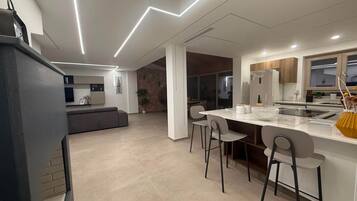 Une cuisine moderne dotée d’un îlot central, de tabourets de bar et d’un coin repas.