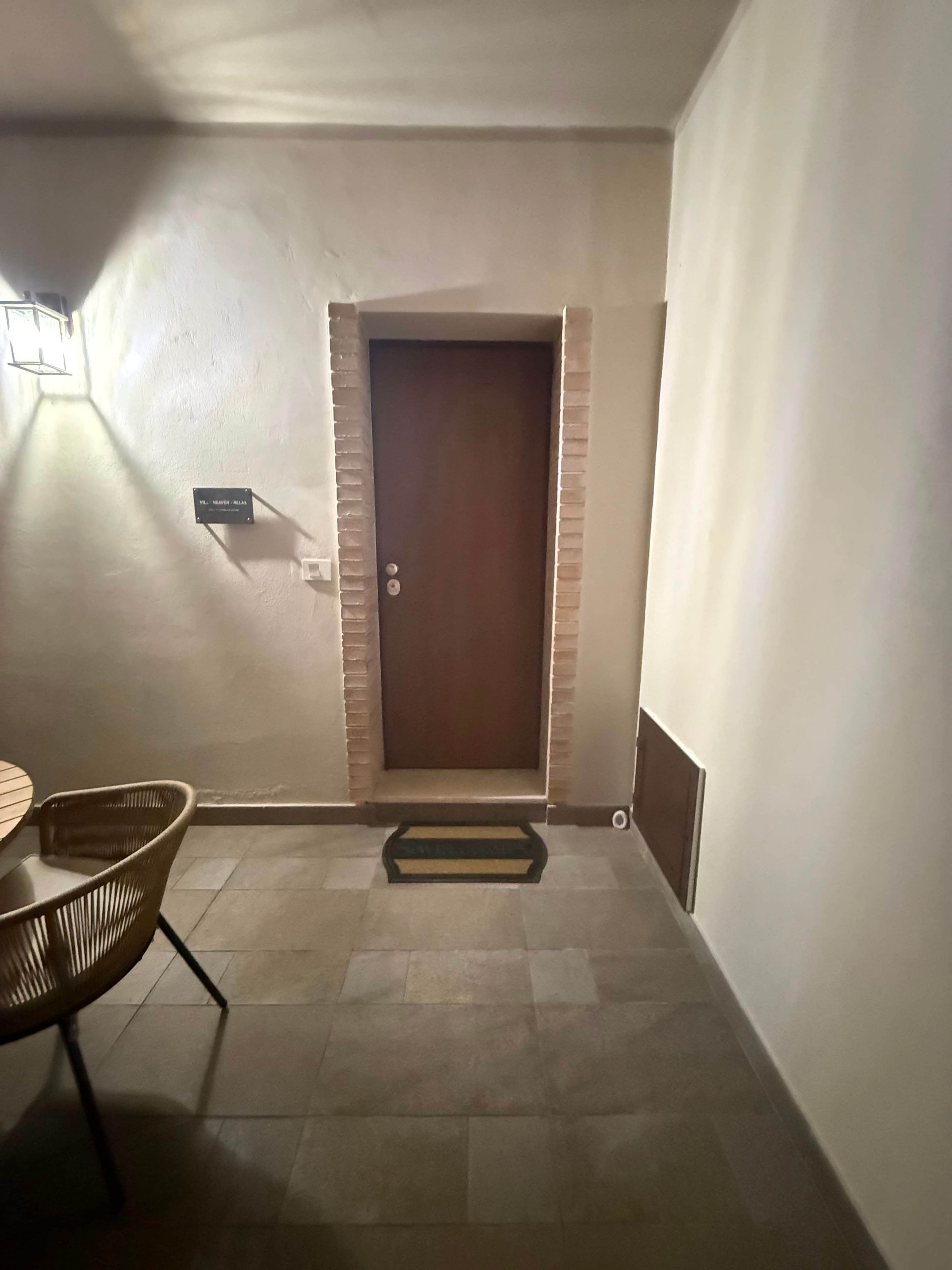 Un couloir avec une porte, une petite table avec des chaises et un paillasson.