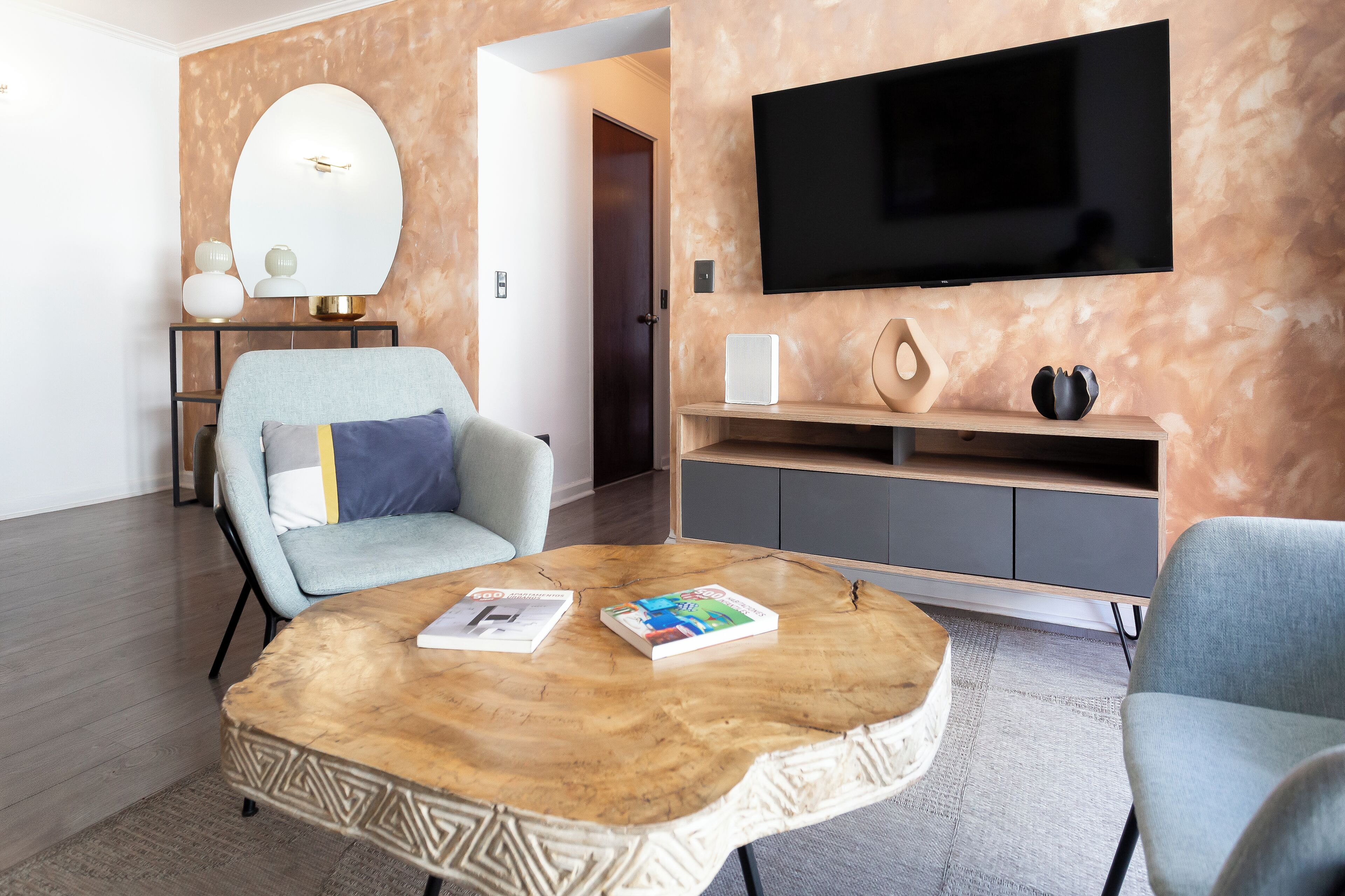 Un salon moderne avec un téléviseur à écran plat, une table basse ronde et un fauteuil confortable.